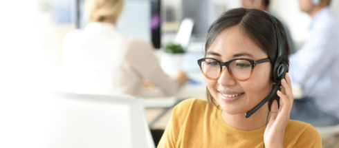 Asian call centre rep wearing glasses and yellow sweat shirt