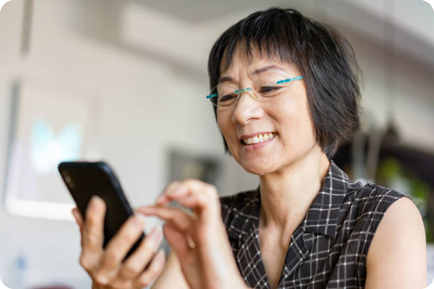 Senior asian lady looking at her smartphone smiling